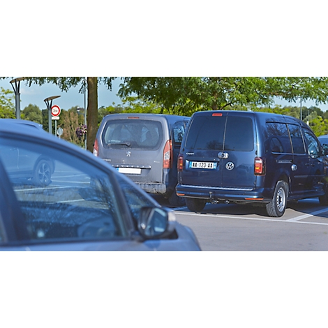 Donkerblauwe auto geparkeerd op een parkeerplaats, omringd door andere auto's.