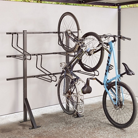 Ein schwarzer Fahrradständer montiert an einer hellen Wand mit einem eingehängten blauen Fahrrad.
