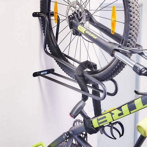 Ein Fahrrad hängt vertikal an einer schwarzen Metall-Wandhalterung, die an einer weißen Wand montiert ist.