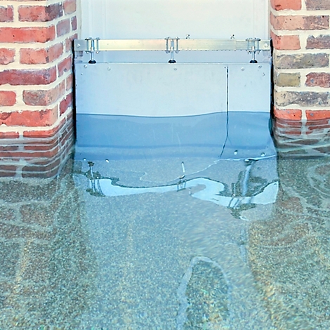 Overstromingsbescherming voor een gebouw gevuld met water. Bakstenen muur links, gladde metalen muur in het midden.