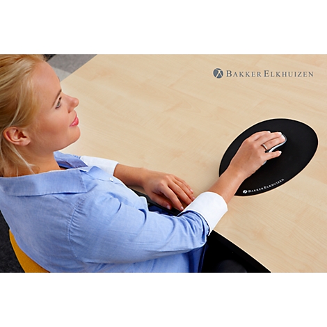 A woman sitting at a desk using a black ergonomic mouse. She is smiling while working.
