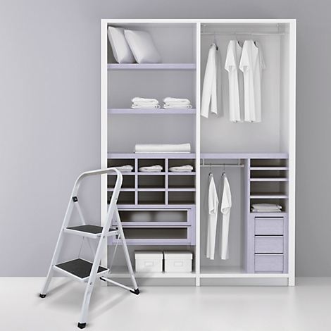 Begehbarer Kleiderschrank mit Kleidung, Kissen, Handtüchern und einer Leiter. Hellgrauer Hintergrund.