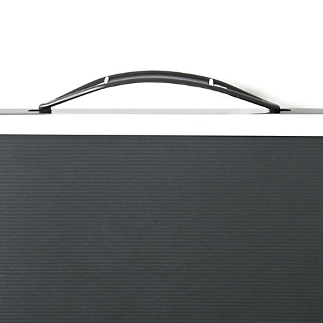 Detailaufnahme eines schwarzen Koffers mit Griff und geriffelter Oberfläche. Der Griff ist leicht gebogen.