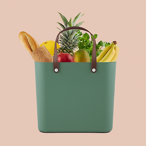 Green shopping bag with brown handles filled with fruits and vegetables.