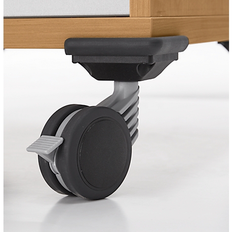 Close-up van een meubelwiel met rem. Het wiel is zwart, de houder grijs. Houten meubels op de achtergrond.