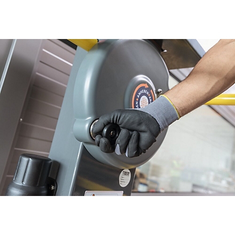Hand met zwarte handschoen draait aan een grijs wiel.