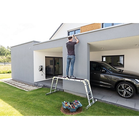 Een man staat op een ladder en werkt aan de buitenmuur van een huis. Op de achtergrond een auto in de garage.