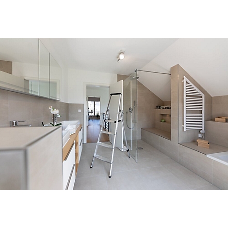 Ruime badkamer met schuine plafonds en moderne meubels. Er staat een ladder in de kamer.