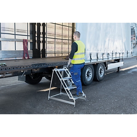 Een man beklimt een ladder naar een vrachtwagen. Hij draagt een gele veiligheidsvest, blauwe broek. De vrachtwagen heeft een wit zeil.