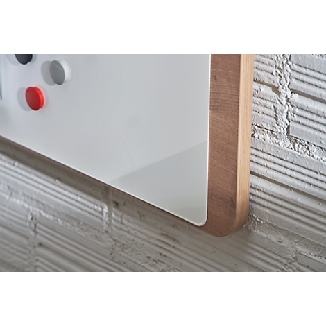 Detail of a white magnetic board with a wooden frame, corner detail, brick wall.