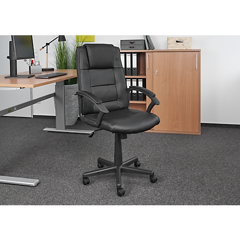 Black office chair in front of a desk and cabinet. The chair is centered, with a padded back, armrests, and casters.