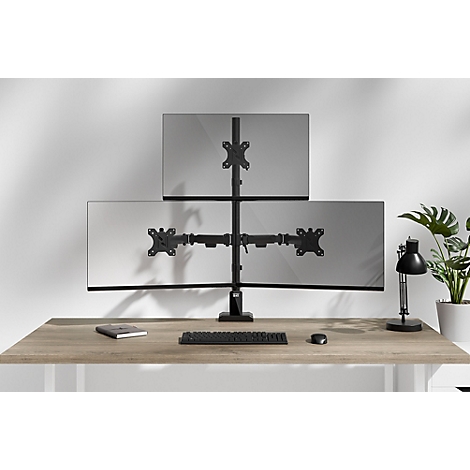 Support triple moniteur avec trois écrans sur un bureau, à côté d'une plante et d'une lampe, clavier et souris.