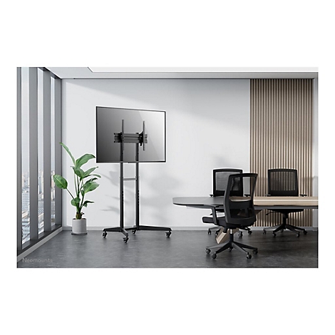 Schwarzer TV-StÃ¤nder mit Bildschirm in einem modernen BÃ¼ro, vor einem Fenster und Tisch.