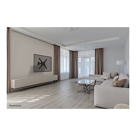 Wohnzimmer mit hellem Parkettboden, hellem Sofa und Fernseher an der Wand. An der Wand ist ein Fernsehhalter montiert.