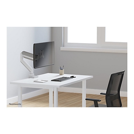 Schreibtisch mit Monitorhalterung. Auf dem Tisch liegen Tastatur, Maus und Notizblock. Im Hintergrund ein Fenster und ein Bürostuhl.