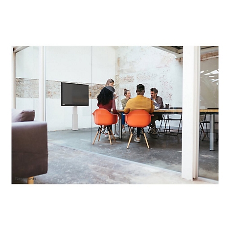 Mehrere Personen sitzen an einem Tisch in einem modernen BÃ¼ro. Orangenfarbene StÃ¼hle und ein groÃŸer Bildschirm.