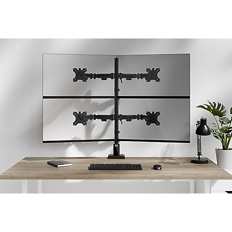 Un support d'écran avec quatre écrans sur un bureau. Clavier, souris, lampe et plante dans l'image.