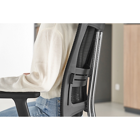 Close-up of a person sitting in an office chair. The chair is black with a mesh back and silver elements.