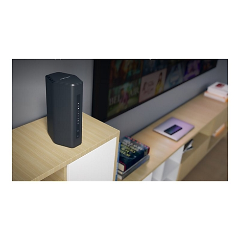 Schwarzer Router steht auf einem Holzschrank vor einem Fernseher.