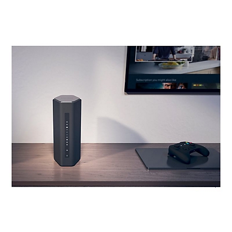 Dunkler, sechseckiger Router auf einem Holztisch. Ein Fernseher und ein Gamepad sind ebenfalls im Bild.