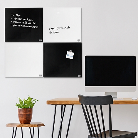 Kantooropstelling: Zwart en wit magnetisch bord met notities, daarnaast een monitor en plant.