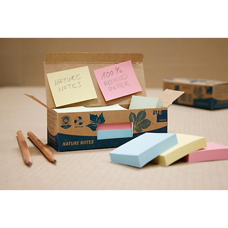 Boîte en carton ouverte avec des blocs-notes, des stylos et des post-its colorés. Sur une note jaune, il est écrit "Nature Notes", sur une rose "100% papier recyclé".