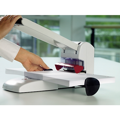 Person using a white paper punch. Red part of the punch is visible.