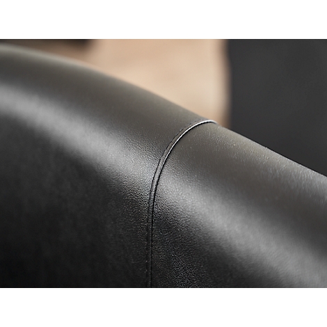 Close-up van een deel van een zwarte leren fauteuil. Zichtbaar zijn naden en de gebogen vorm van het leer.