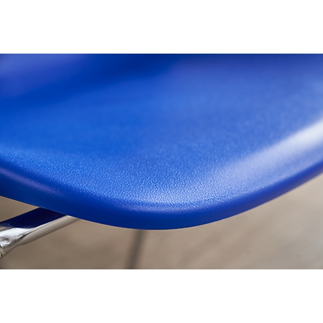 Nahaufnahme eines blauen Stuhlsitzes mit abgerundeter Kante. Chromfarbene Stuhlbeine im unteren Bildbereich.