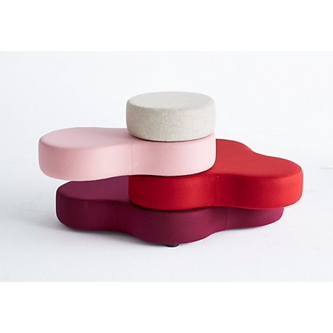Vier farbige Hocker in Rosé, Rot und Beige. Der größte Hocker hat die Form einer Blume, der kleinste eine runde Form.