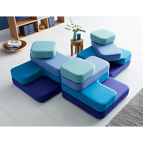 Modulares Sofa in verschiedenen Blautönen, quadratische Kissen auf den Elementen.