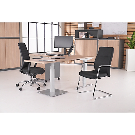 Een bureau met twee bureaustoelen, een monitor en een laptop, staand in een kantoor.
