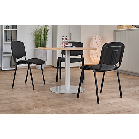 Drei Stühle um einen runden Tisch im Büro. Der Tisch hat eine Holzplatte, die Stühle sind schwarz.