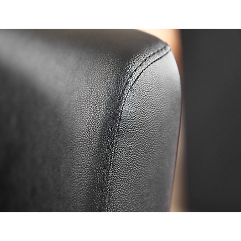 Gros plan sur une surface en cuir noir avec une couture gris clair. La texture est légèrement rugueuse.