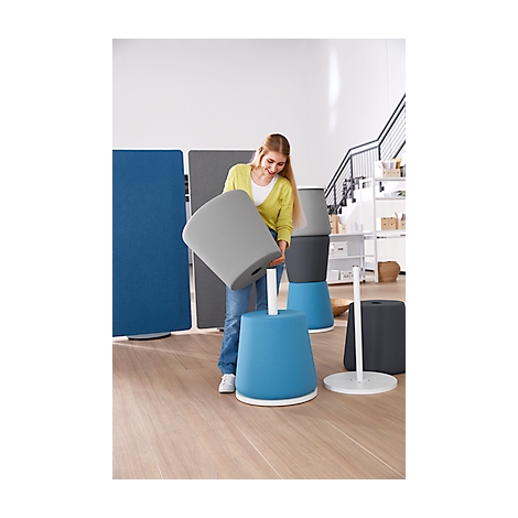 A woman placing a gray stool on a blue one, she smiles.