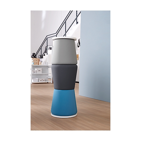 Stackable chair of three elements in gray, blue, and gray tones. Stands on wooden floor in front of stairs.