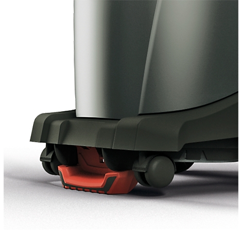 Close-up of the lower parts of a vacuum cleaner. Black base with red accents and small rollers for mobility.