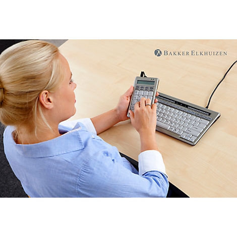 A woman in a blue shirt sits at a table using a calculator and a small keyboard. The Bakker Elkhuizen logo is visible in the background.