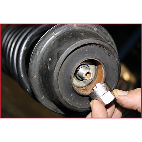 Nahaufnahme eines Stoßdämpfers, der mit einem Schraubenschlüssel bearbeitet wird.