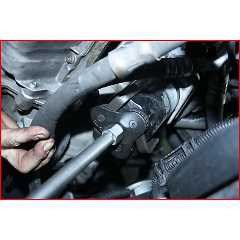 Nahaufnahme der Montage eines Ölfilters mit einem Spezialwerkzeug im Motorraum.