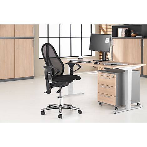 Black office chair in front of desk with screen, mobile pedestal, and windows.