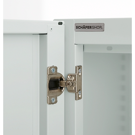 Close-up of a white cabinet with silver hinge. The logo "SCHÄFERSHOP" is visible.