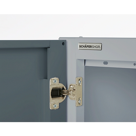 Close-up of a hinge on a gray cabinet door, next to a part of the cabinet with logo.