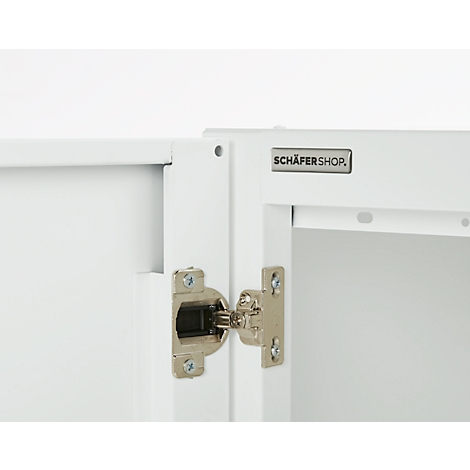 Close-up of a white cabinet with a silver-colored hinge opening. The "SCHÄFER SHOP" logo is visible.