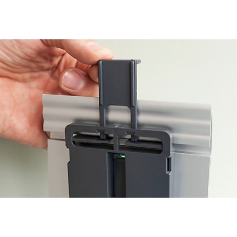 Person holding grey plastic part over a silver rail. The part is being inserted.