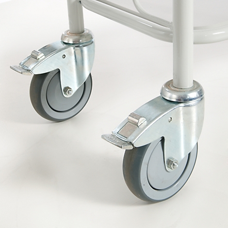 Close-up of two casters with brakes, mounted on a metal frame. The casters are gray, the frame parts are silver.