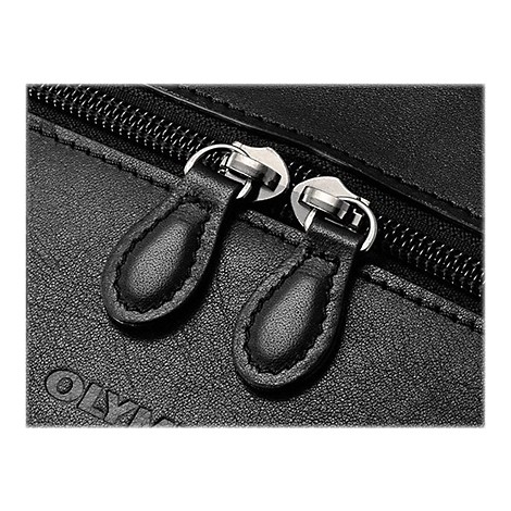 Gros plan sur deux tirettes de fermeture éclair en cuir noir et une fermeture éclair argentée sur du cuir noir.