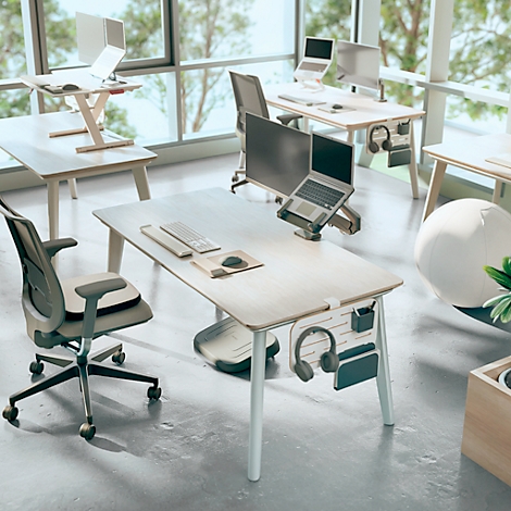 Bureau avec plusieurs bureaux, chaises et ordinateurs portables. Fenêtres en arrière-plan.