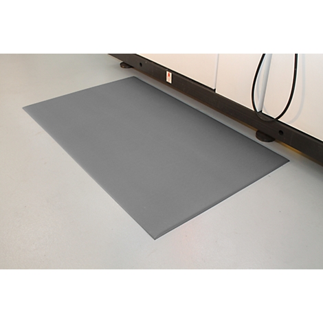 Gray mat in front of a machine on white floor. Black cable and machine parts visible.