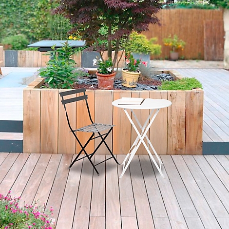 Een gezellige hoek in de tuin met tafel en stoel. Op de achtergrond een houten terras met beplanting.